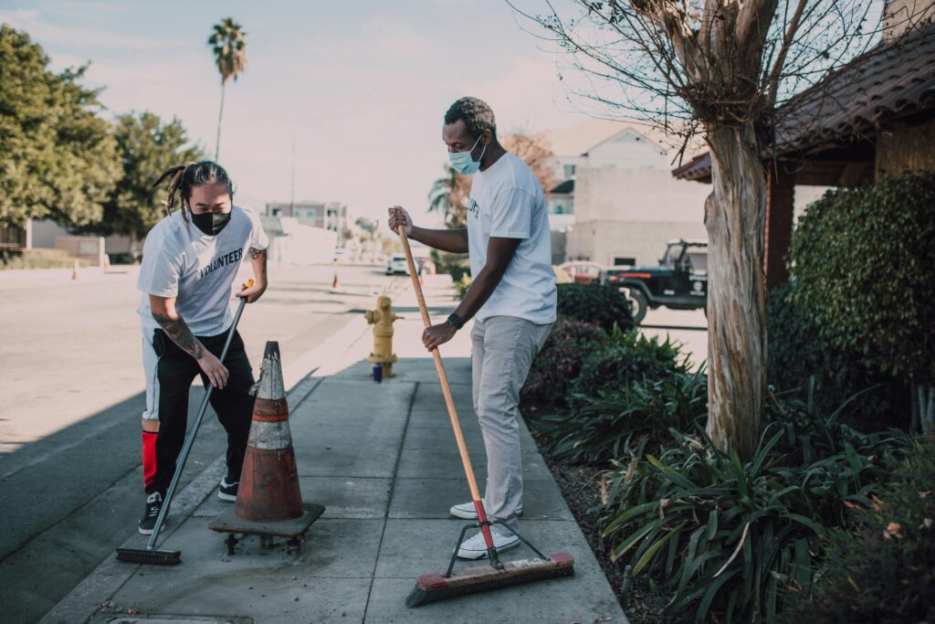 Two volunteers engaged in a street cleaning effort, promoting social good and community service.
